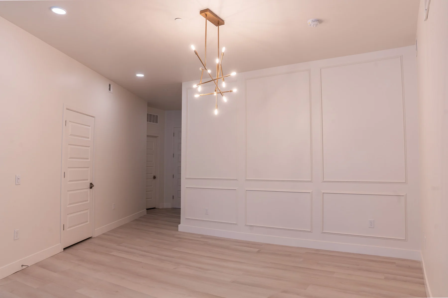 Living room with paneled walls and a modern chandelier